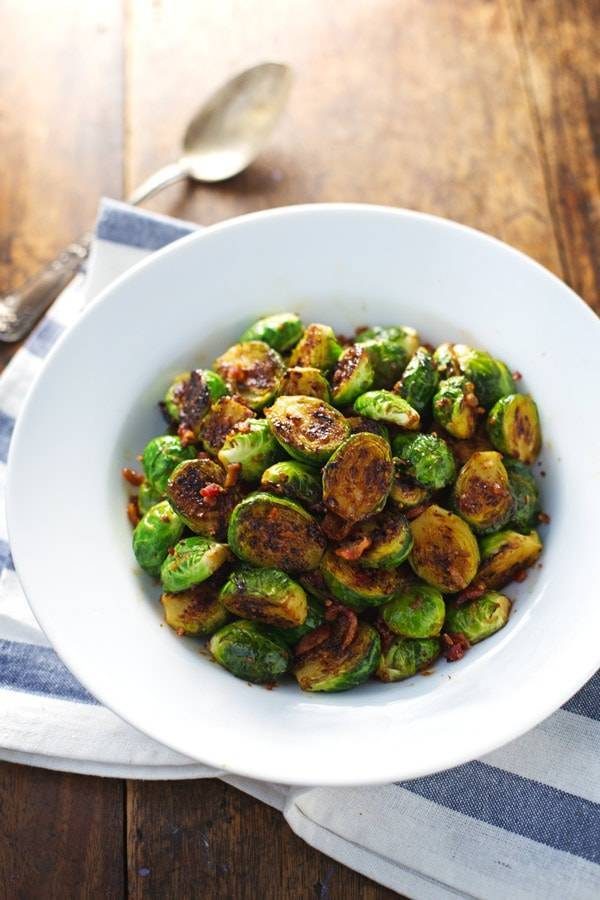 Caramelized brussels sprouts in a blue bowl with a spoon.