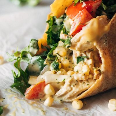 Juicy close up of the chicken wrap with toppings falling out.